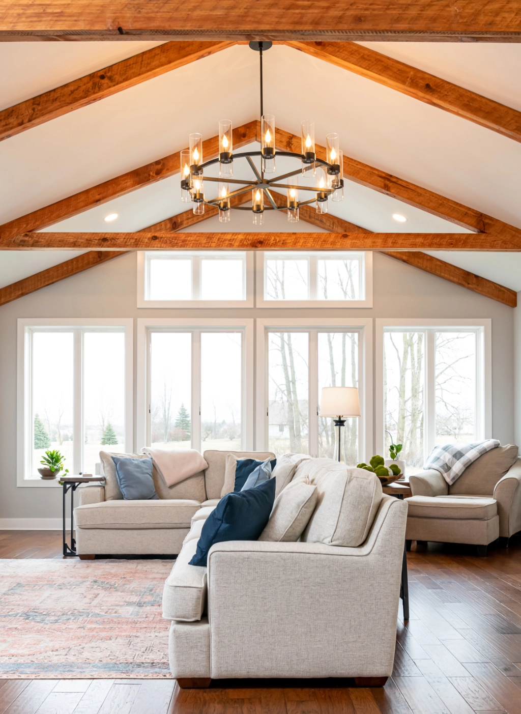 A newly renovated living space with wooden beams and gray couches.